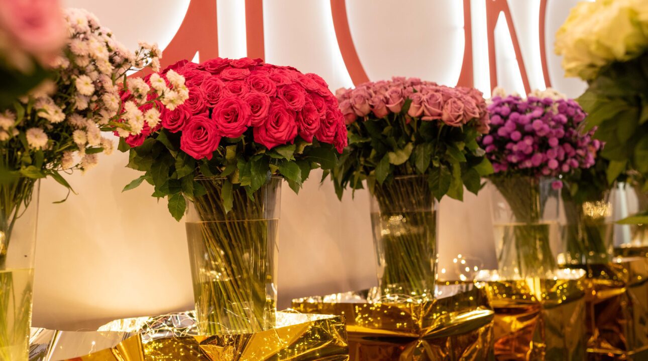 A stunning display of vibrant rose bouquets at the Baraka Roses stand during IFTEX 2024. The arrangement features an array of pink, red, and purple roses, elegantly presented in clear vases with golden wrapping and fairy lights, showcasing the exceptional quality and beauty of Baraka Roses